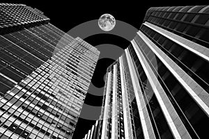 Skyscraper buildings at night with a full moon