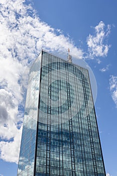Skyscraper in business district against blue sky. Modern corporate building and architecture