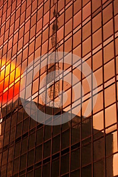 Skyscraper Business Office glass wall refleting red sun and antenna