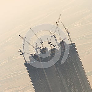 Skyscraper construction site with cranes on top of buildings.