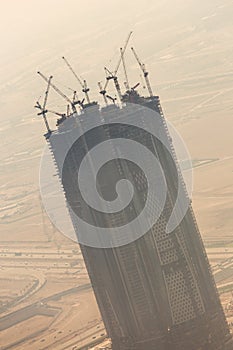 Skyscraper construction site with cranes on top of buildings.