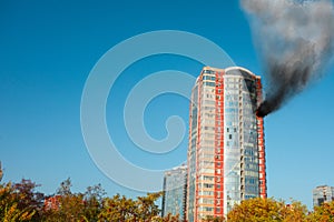 Skyscraper fire accident. Concept of firefighting problems at the height. Thick smoke billows from a window of apartment or office