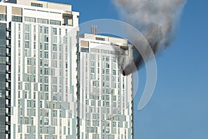 Skyscraper fire accident. Concept of firefighting problems at the height. Thick smoke billows from a window of apartment or office