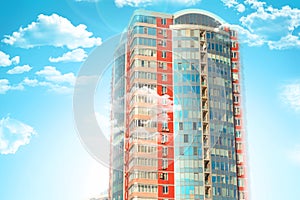 Skyscraper or flat block building on clouds and blue sky background. Closeup view of modern urban architecture landscape cyan