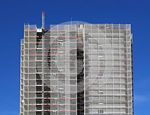 skyscraper with scaffolding of construction site for installation of insulating panels for the reduction of resource waste photo