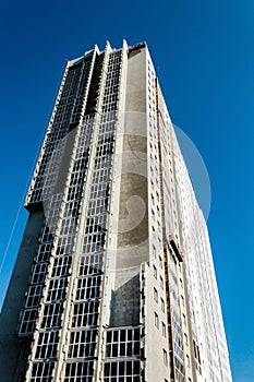 Skyscraper under construction on the background of clear blue sky with an external front elevator without people