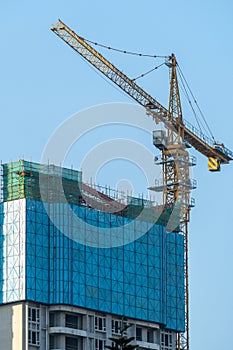skyscraper is under construction, the crane is working under the blue sky.