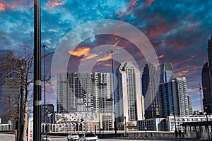 Skyscrapers and buildings in the city skyline with a tower crane and tall black light posts with blue and red sky