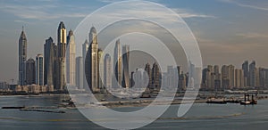 Skyscrapers of Dubai Marina at sunset, with the sun glinting of the glass of the modern buildings.