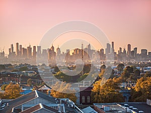 Skyscrapers in Melbourne`s CBD in morning mist. Elevated view overlooking residential houses in western suburbs.