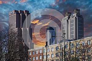 Skyscrapers and office buildings in the city skyline with bare winter trees and powerful clouds at sunset in Atlanta Georgia