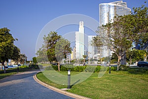 Skyscrapers surrounded by a green park of palm trees on La Corniche promenade in Abu Dhab