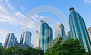 Skyscrapers under morning sun against blue sky with light clouds.