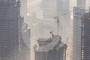 Skyscrappers construction site with cranes on top of buildings.