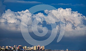 Skyscrappers near sea with stormy clouds as hat