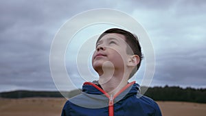 Skyward Gaze: Enthralled Boy Standing in a Field, Observing the Sky