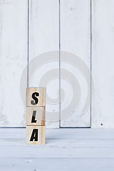 sla concept written on wooden cubes or blocks, on white wooden background.