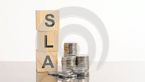 SLA - text on wooden cubes on white background with coins