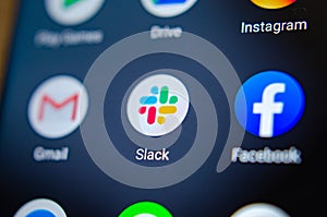 Slack app on the smartphone screen and a finger launching it. The top app for communication and collaboration