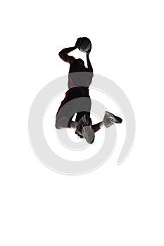 Slam dunk. Silhouette of young man, basketball player in motion during game throwing ball into basket isolated on white
