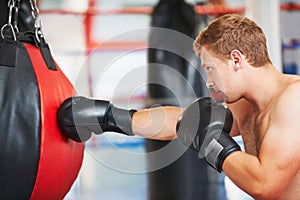Slamming the bag. A young boxer practicing with a punching ball at the gym.