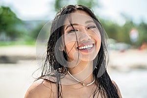 Sland girl. Beautiful, natural asian woman with wet hair and big toothy smile looking at the camera, enjoying sunny day on the