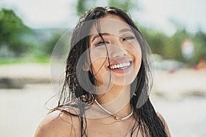 Sland girl. Beautiful, natural asian woman with wet hair and big toothy smile looking at the camera, enjoying sunny day on the