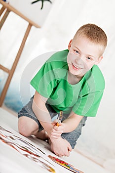 Slanted view of boy kneeling on painting