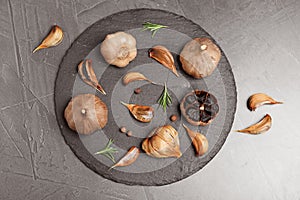 Slate plate with aged black garlic and rosemary on gray background