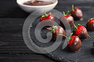 Slate plate with chocolate covered strawberries on table