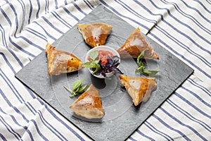 Slate plate with delicious samosas on gray background