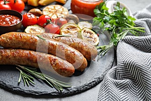 Slate plate with delicious sausages and vegetables served for barbecue party