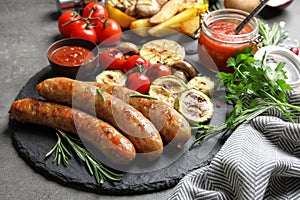 Slate plate with delicious sausages and vegetables served for barbecue party photo