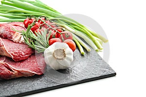 Slate plate with fresh raw meat, vegetables and herbs on white background