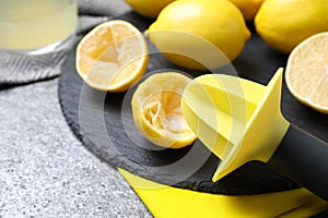 Slate plate with lemon reamer and squeezed fruit on table, closeup