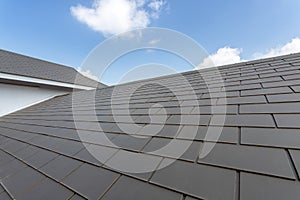 Slate roof against blue sky, Gray tile roof of construction house with blue sky and cloud background