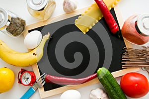 Slate, tomatoes, banana, red paper, lemon, egg, fork, clock, pasta, garlic, spices and cucumber on white background. Cooking at ho