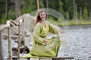 Woman by the water with a wreath in her hands