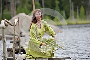 Woman by the water with a wreath in her hands