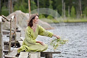 Woman by the water with a wreath in her hands