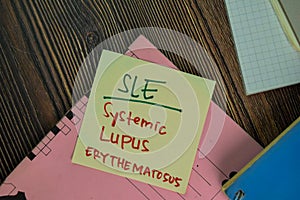 SLE - Systemic Lupus Erythematosus write on sticky notes isolated on Wooden Table