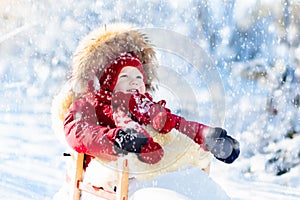 Sled and snow fun for kids. Baby sledding in winter park.