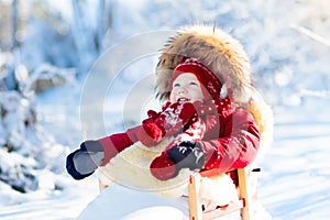 Sled and snow fun for kids. Baby sledding in winter park.