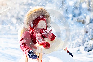 Sled and snow fun for kids. Baby sledding in winter park.