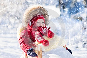 Sled and snow fun for kids. Baby sledding in winter park.