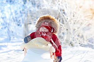 Sled and snow fun for kids. Baby sledding in winter park.