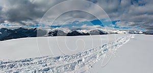 Sledge trace and footprints on winter mountain hill top