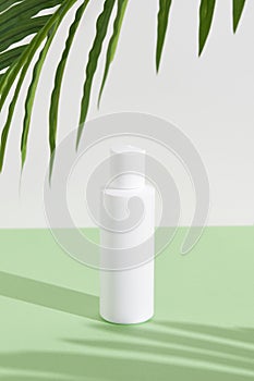 A sleek bottle of cosmetic cream casts captivating shadows on a lush green backdrop in minimalist style