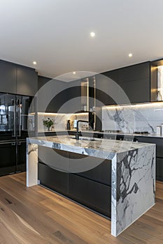 Sleek modern kitchen with black marble countertops and dark cabinetry photo