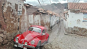 Sleek red Volkswagen Beetle parked in an urban area, nestled alongside a street curb